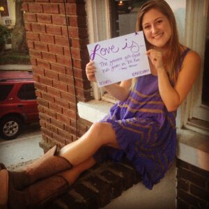 Emily holding a "Love is..." sign